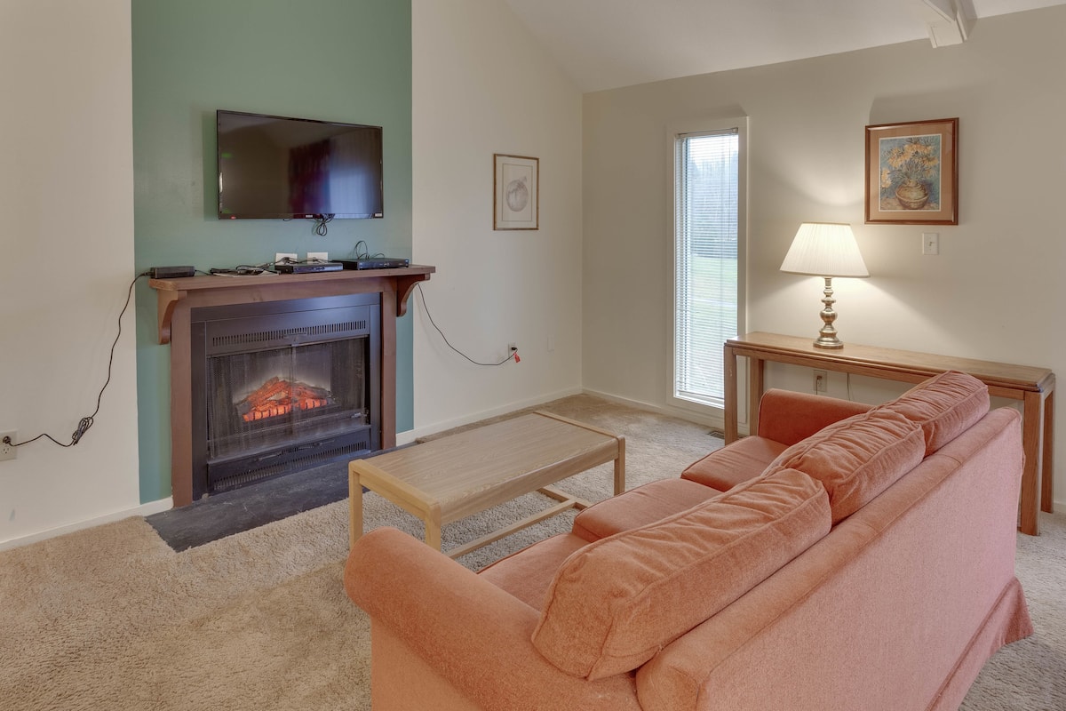A living room with a fireplace, a television mounted above it, a sofa, a coffee table, and a lamp on a side table.