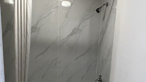 A bathroom with a marble shower wall, a bathtub, and a toilet. - Deluxe INN  Augusta (Augusta)