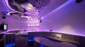 A modern, well-lit room with a curved seating area, a bed, and a flat-screen TV. - Wego Boutique Hotel Linsen (Taipei)