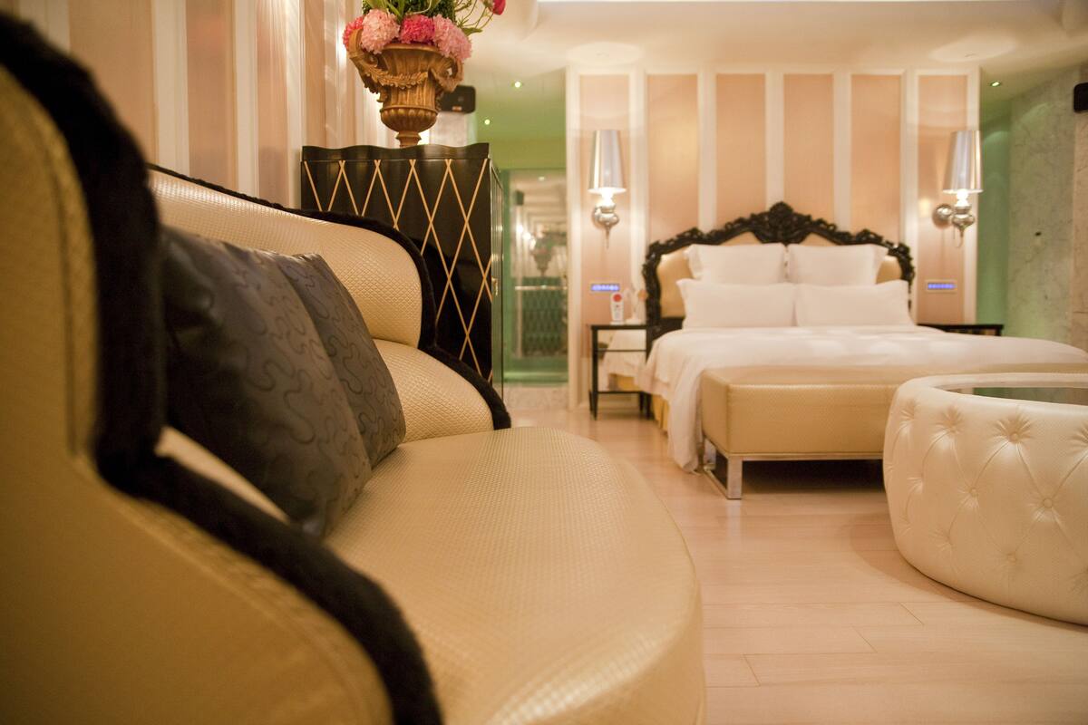 Une chambre d’hôtel comprenant un lit, un canapé, une table de chevet et un vase décoratif.