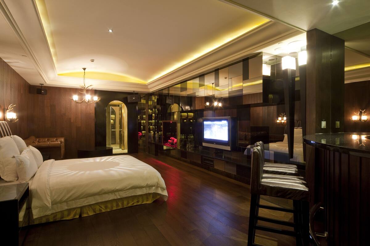 Une chambre d’hôtel avec un grand lit, une télévision, un coin bar et un miroir.