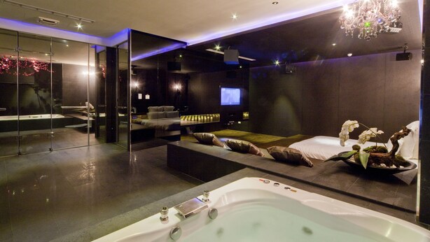 A modern spa room with a large bathtub, a sofa, and a television. - Wego Boutique Hotel Linsen (Taipei)