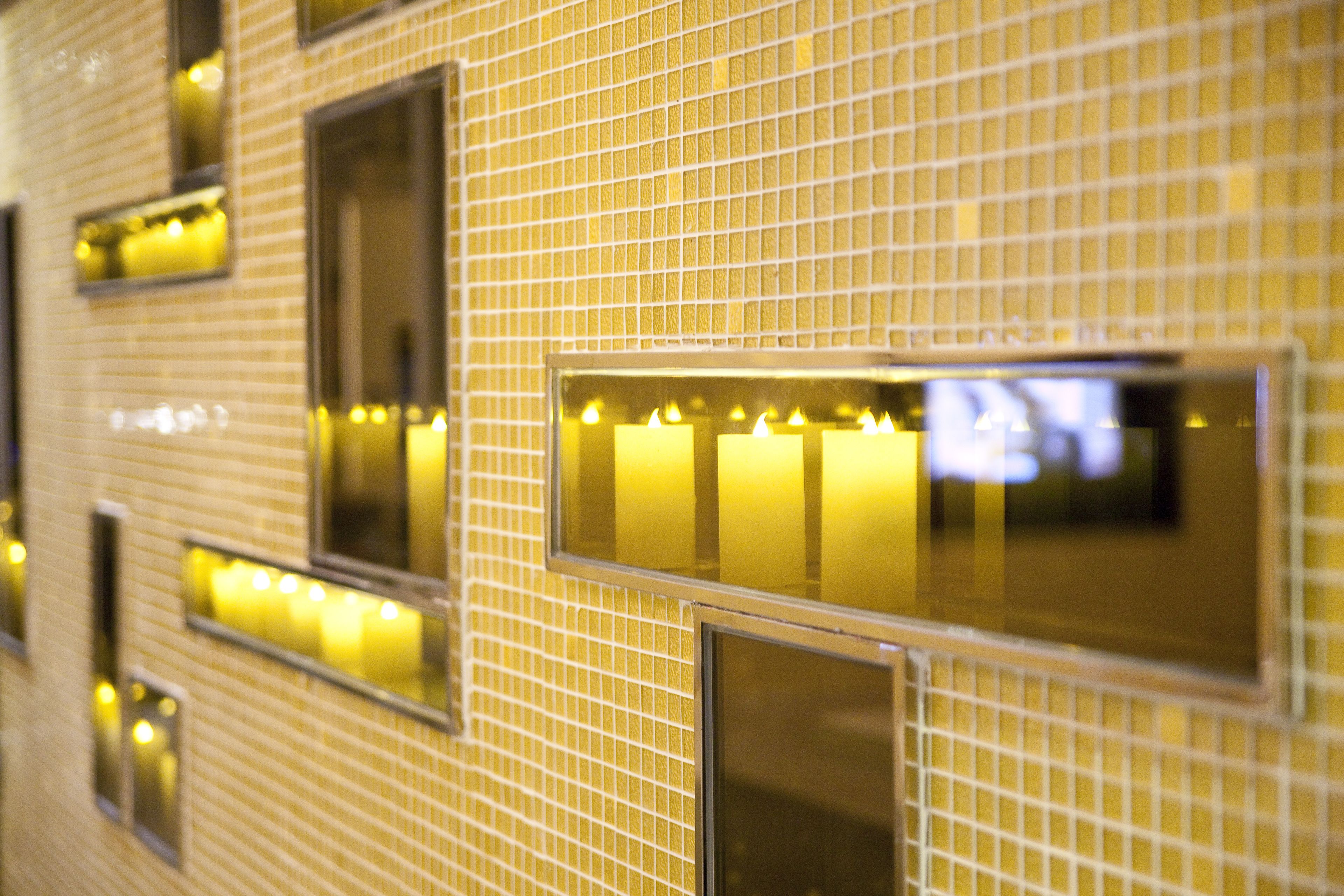 A wall with a grid pattern and rectangular windows with illuminated interiors.