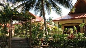 A tropical resort with a covered walkway leading to a building with a red roof. - Aqua-Landia Resort (Dauin)