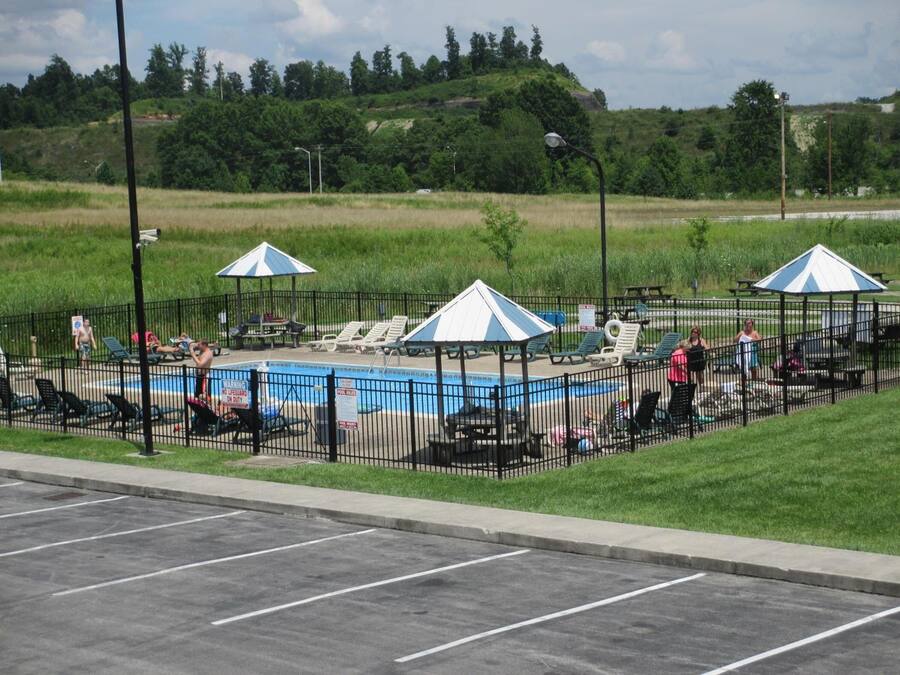 A swimming pool area with lounge chairs and umbrellas, surrounded by a fence.