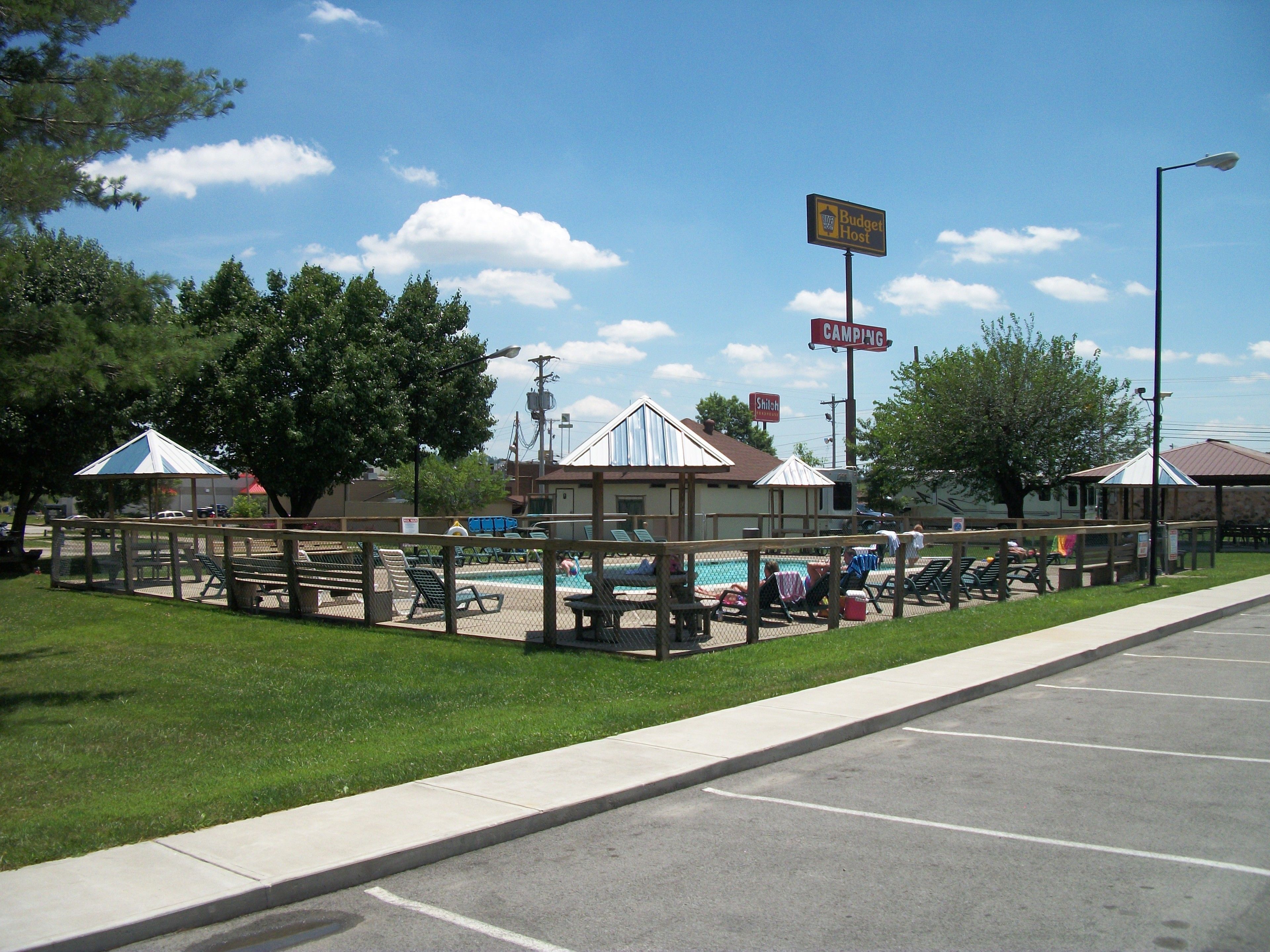 A campground with a swimming pool, picnic tables, and a fenced area.