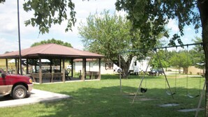 A park with a covered picnic area, swings, and a red truck parked nearby. - Budget Host Westgate Inn (London)