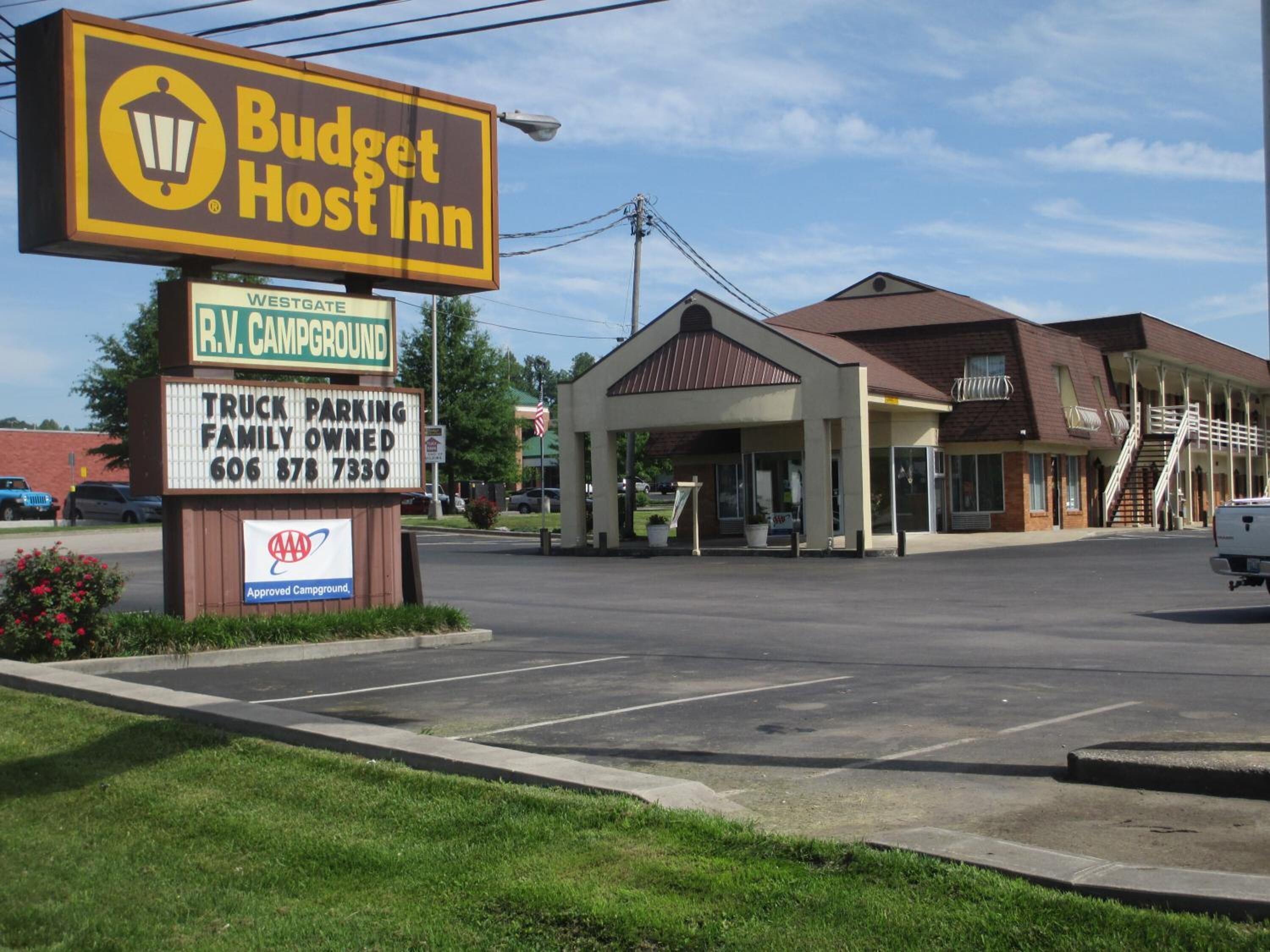 Un motel economico con un grande cartello, un'area di parcheggio per camion e un edificio dotato di rampa e scale.