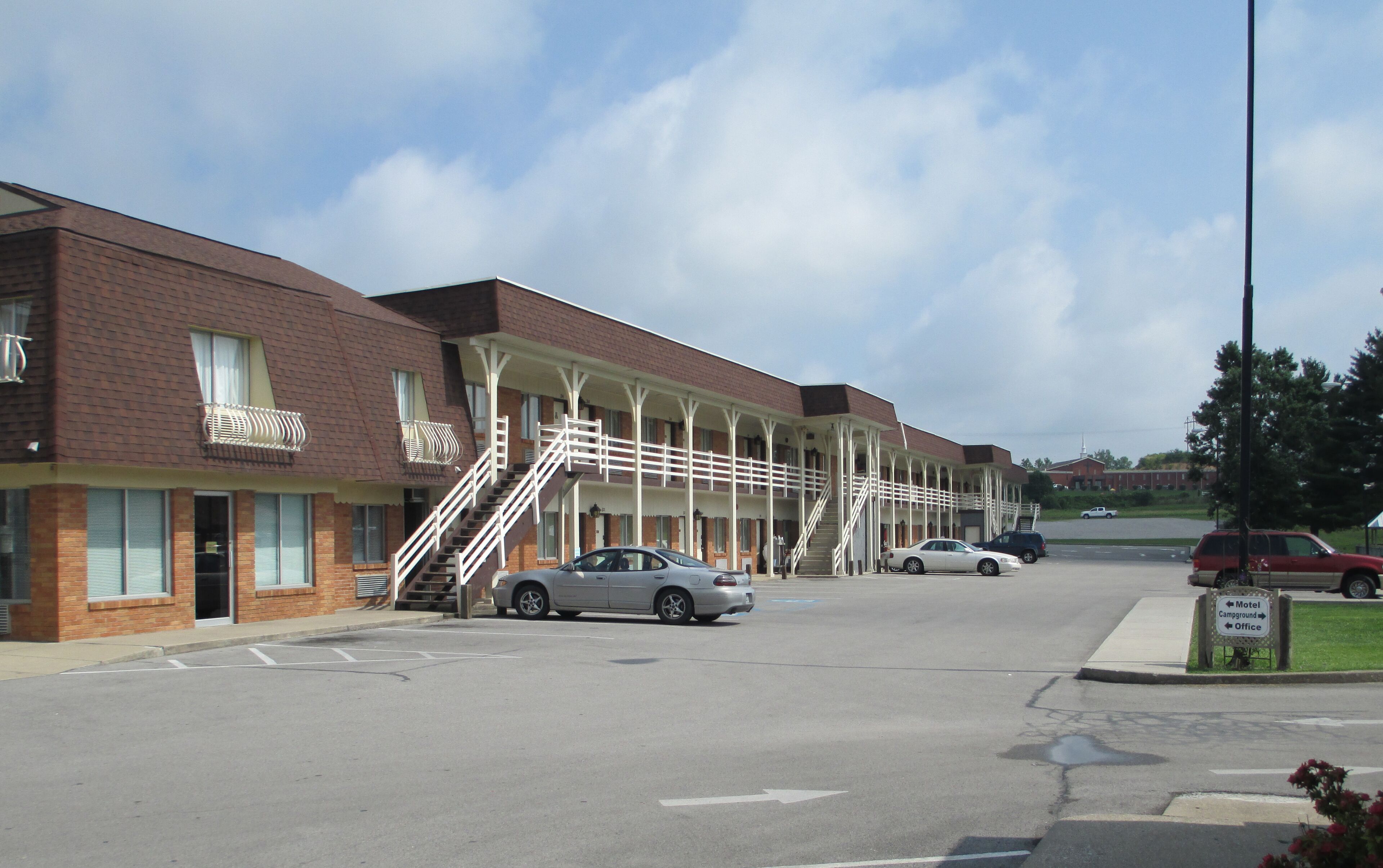 A motel with a brick facade, multiple balconies, and a covered parking area.