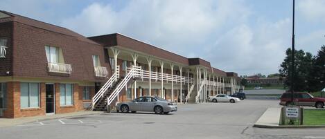 A motel with a brick facade, multiple balconies, and a covered parking area.