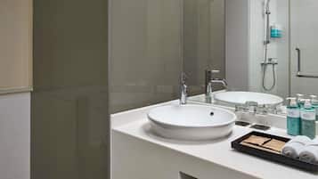 A modern bathroom with a glass shower enclosure, a white sink, and a mirror.