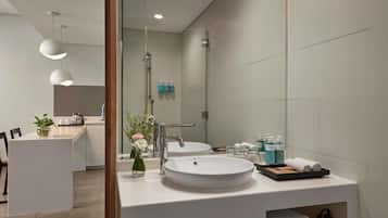 A modern bathroom with a large mirror, two sinks, and a vanity area with toiletries.