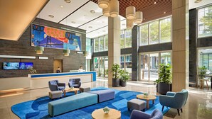 A modern lobby with a reception desk, seating area, and large windows. - Novotel Living Saigon South (Ho Chi Minh City)