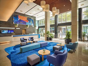 Eine moderne Lobby mit einer Rezeption, einer Sitzecke und großen Fenstern.