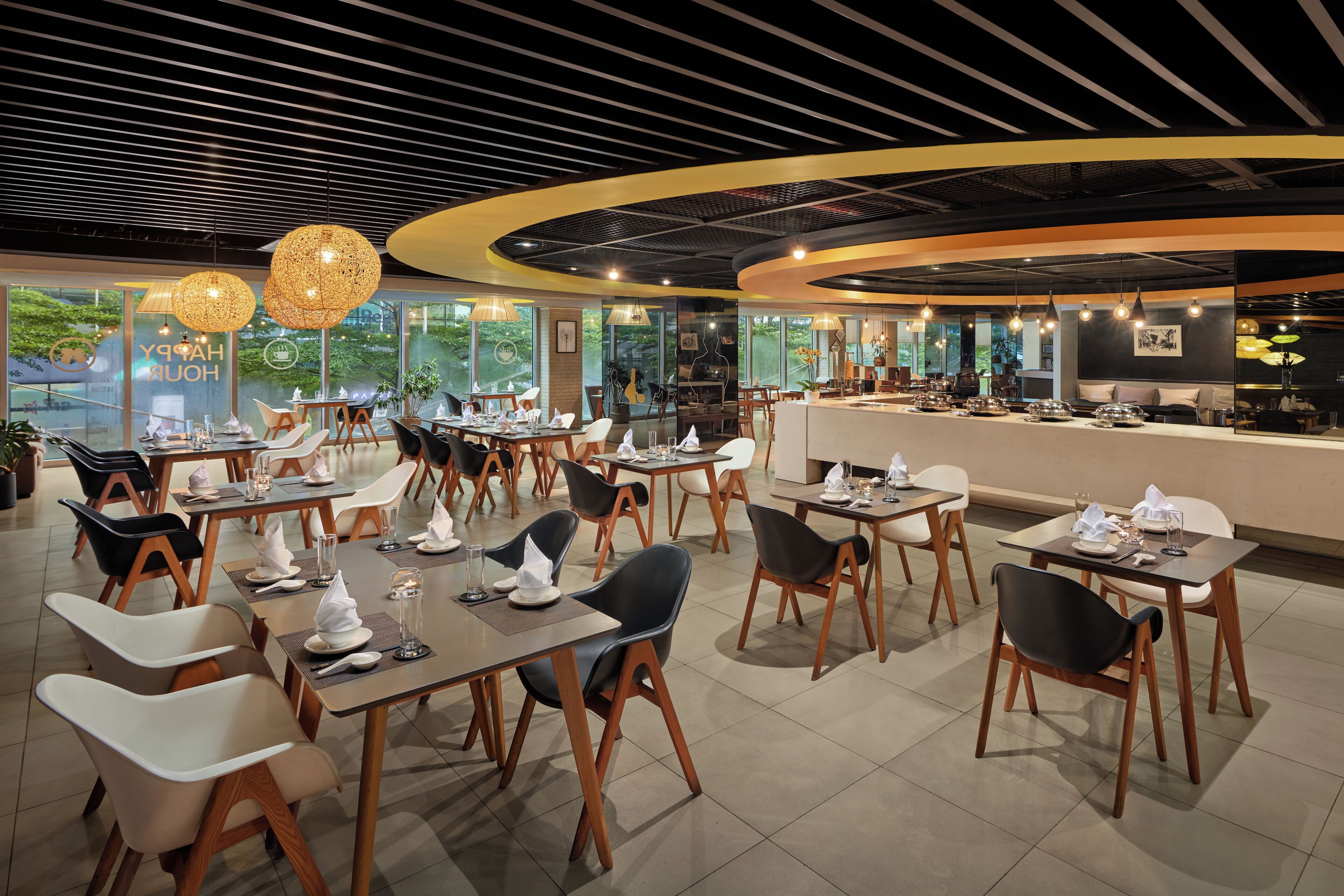 A modern restaurant with round tables, black and white chairs, and a curved counter.