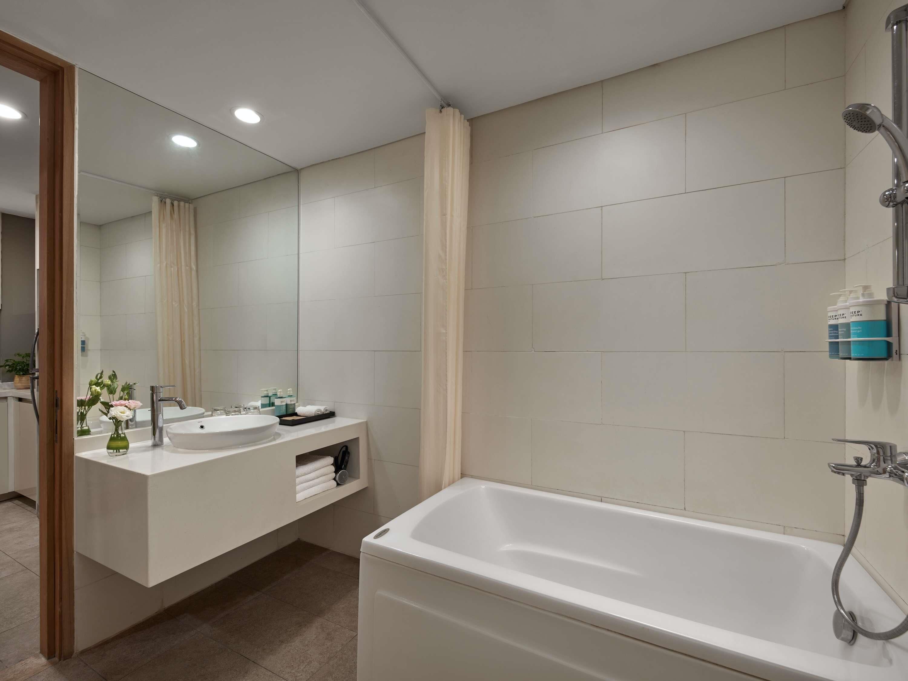 Un baño moderno con un espejo grande, dos lavamanos, una bañera y una ducha.