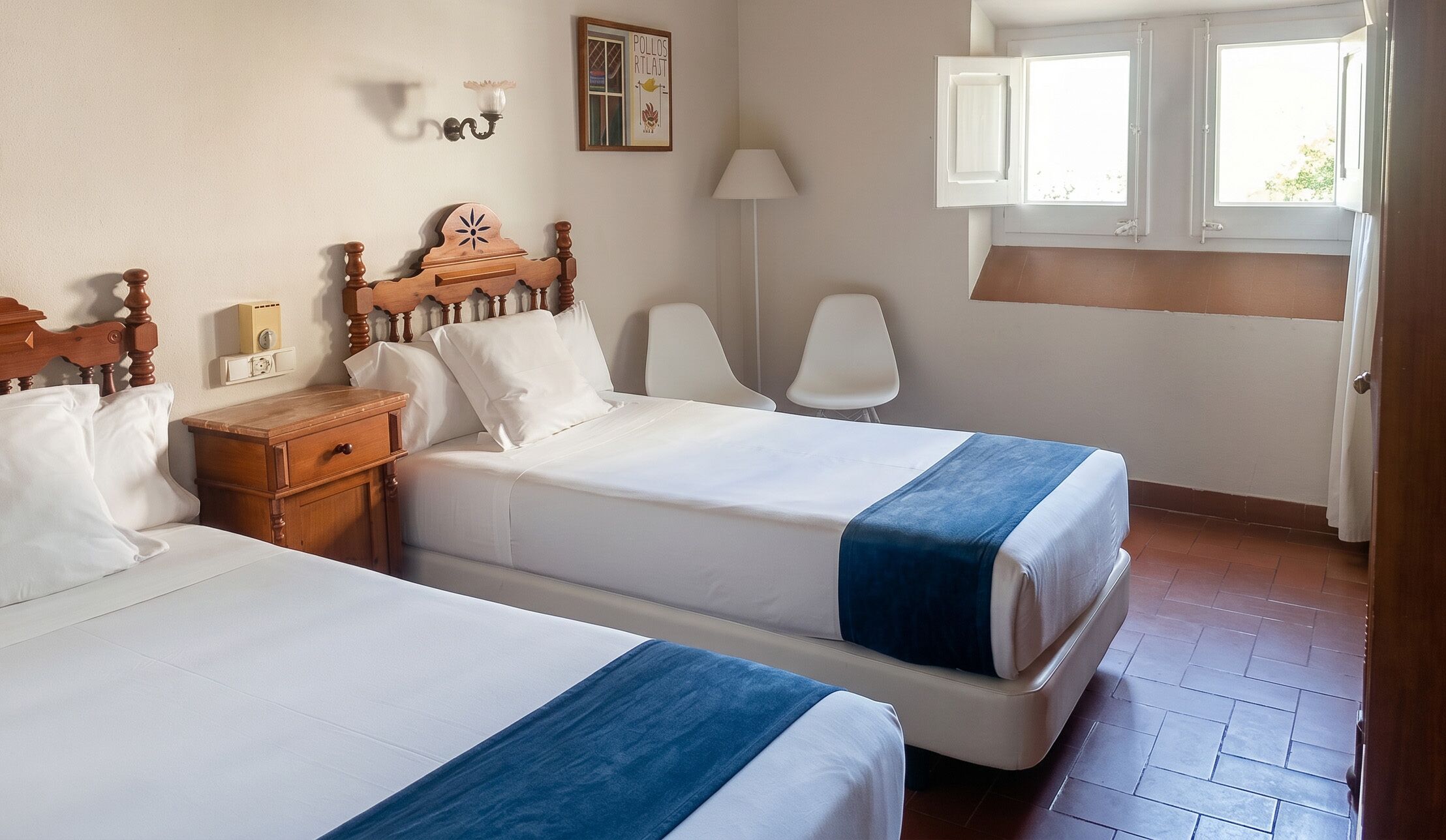 Una habitación de hotel con dos camas, una mesita de noche, una lámpara, una silla y una ventana con cortinas.