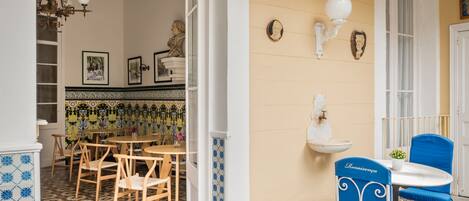 Un comedor con mesa y sillas, una araña y adornos en la pared.
