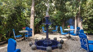 A garden patio with blue chairs and a central fountain.