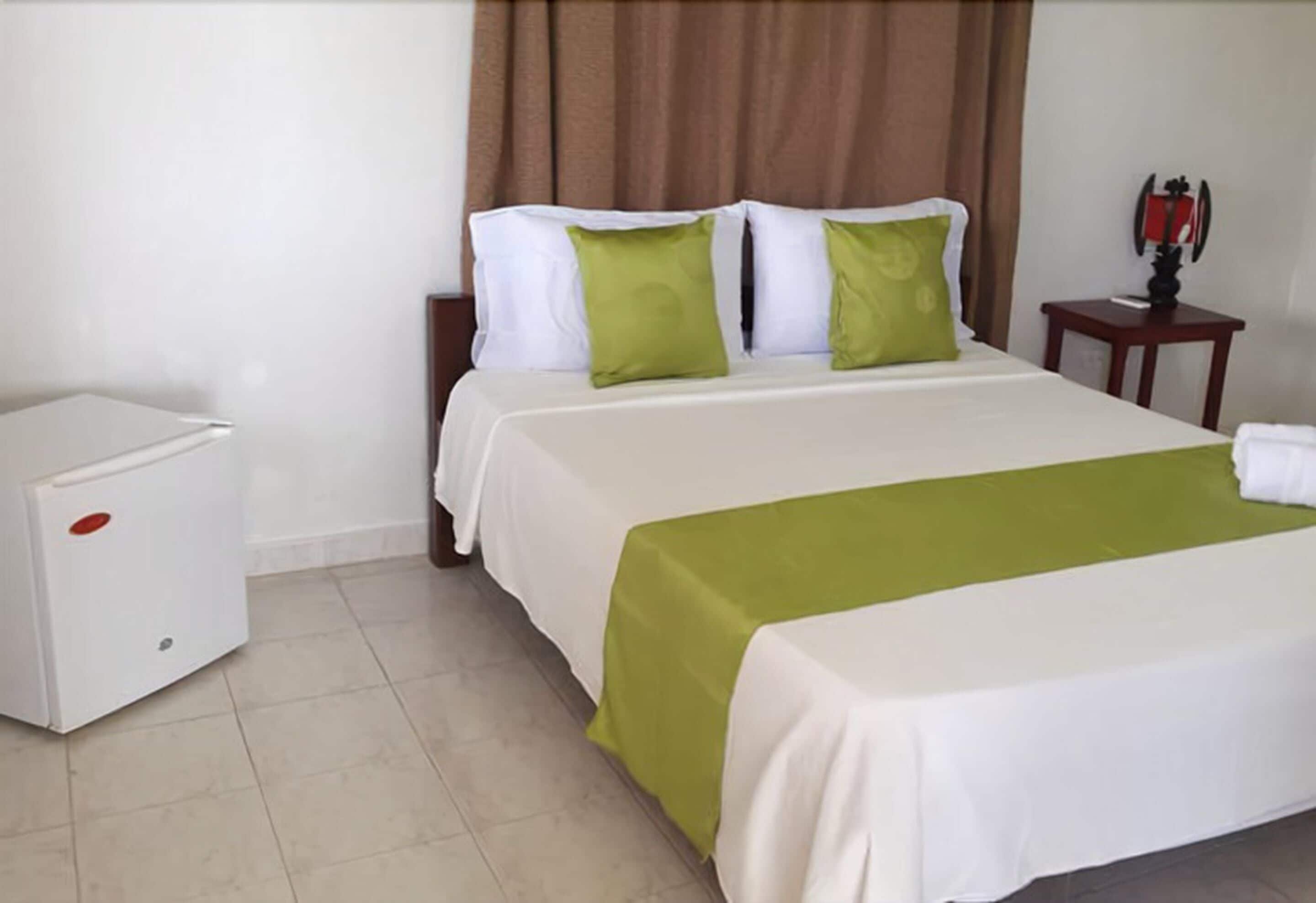 Une chambre d’hôtel avec un lit, une table de chevet et une petite table avec une lampe.