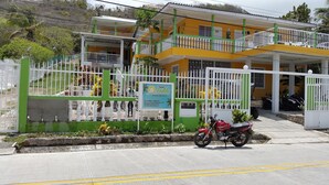Un bâtiment à deux étages doté d’un balcon, d’une enseigne et d’une moto garée devant.