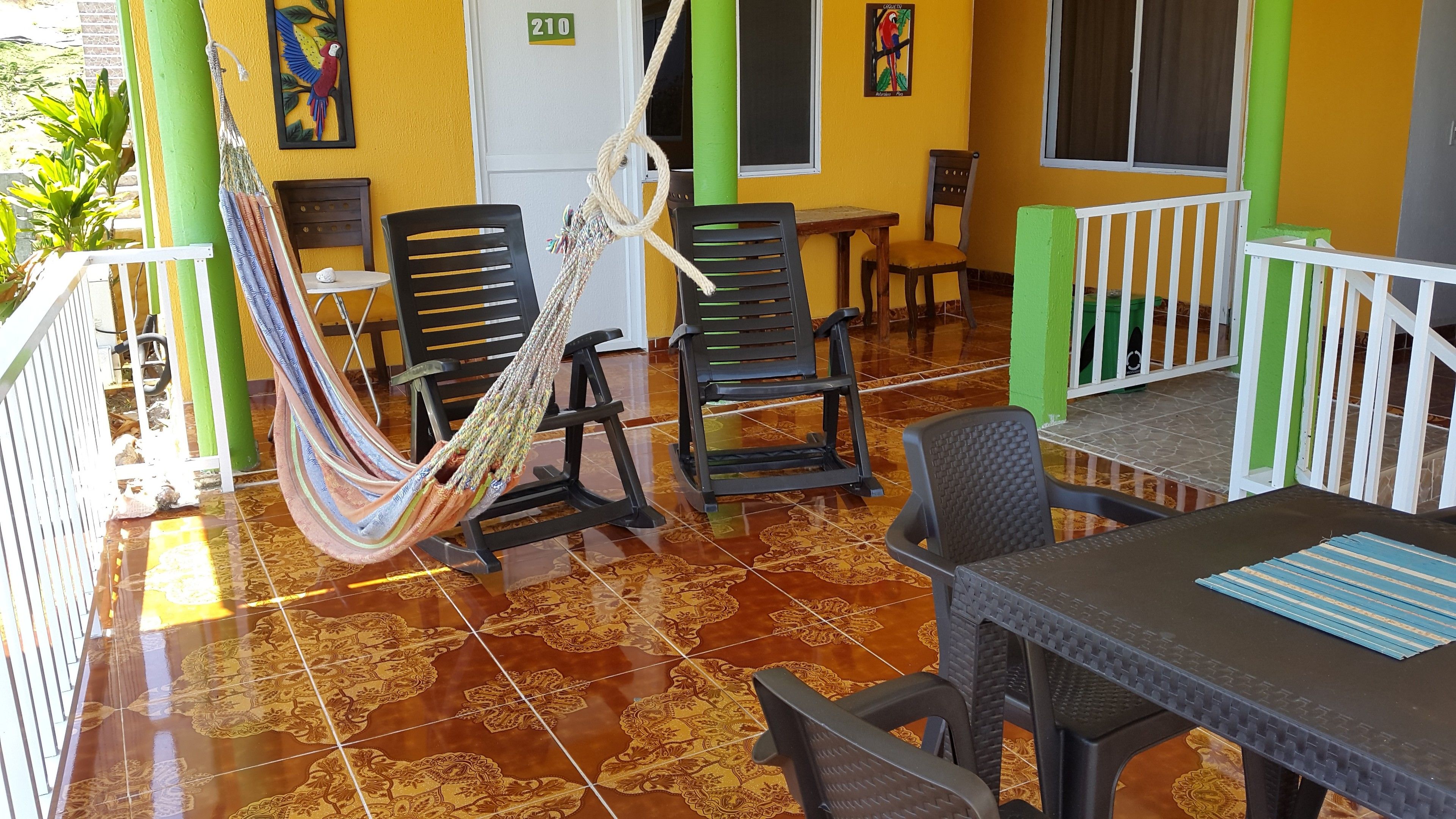 Quarto com rede, cadeiras, mesa e vista para o exterior.