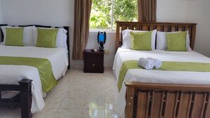Une chambre d’hôtel avec deux lits, chacun agrémenté de draps verts et blancs, une petite table de chevet en bois avec une machine à café, et une fenêtre avec des rideaux.