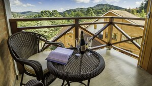 Un balcon avec des fauteuils en osier et une table, une bouteille de vin et des verres.