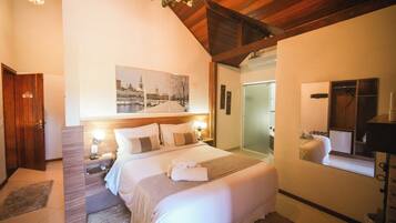 Quarto de hotel com uma cama grande, mesas de cabeceira, um espelho e um quadro na parede.