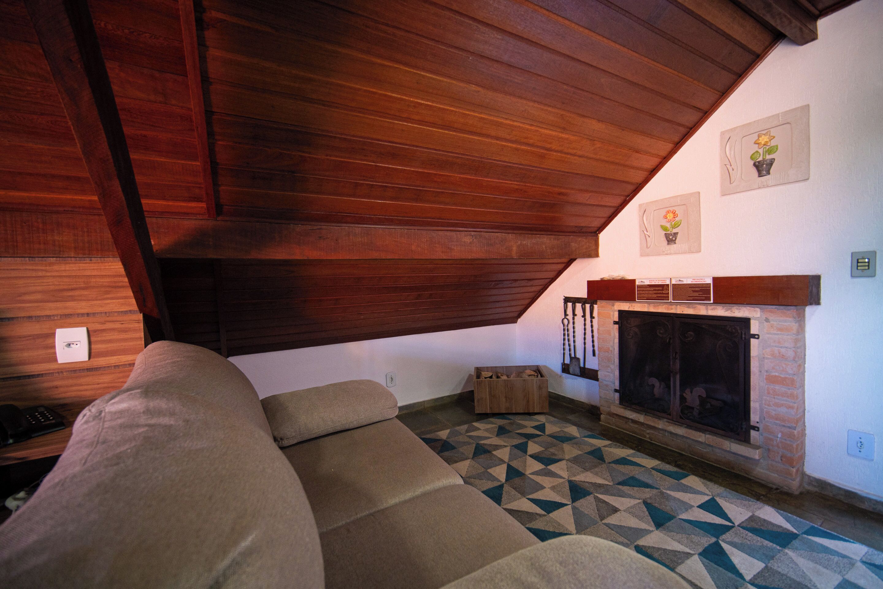 Una sala de estar acogedora con techo de madera, chimenea, suelo estampado y un sofá.