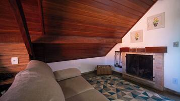 A cozy living room with a wooden ceiling, a fireplace, a patterned floor, and a sofa.