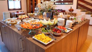 Un buffet garni de divers fruits et plats, des meubles en bois et un vase à fleurs.