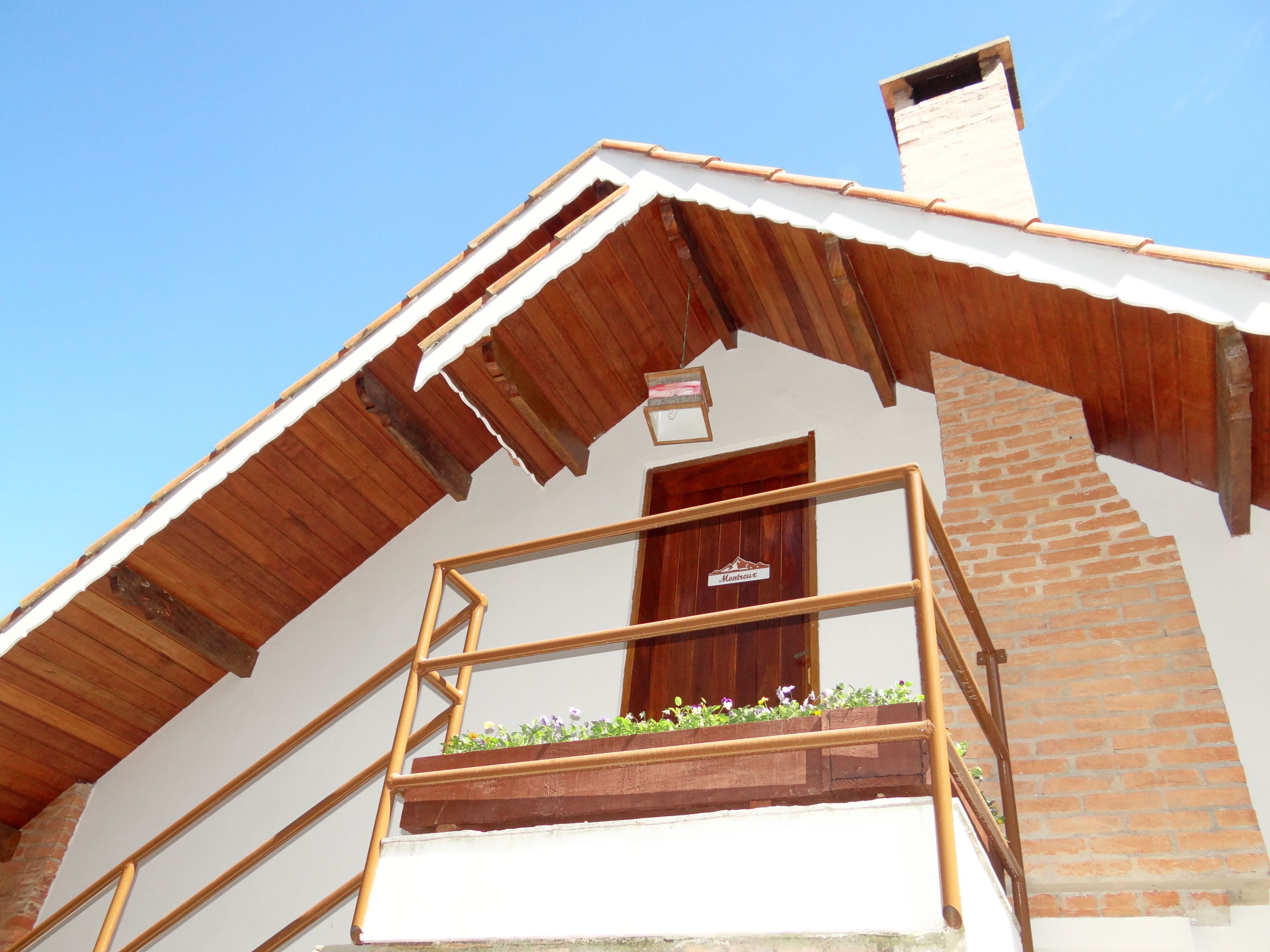 Un edificio tradicional con tejado inclinado, escalera de madera y un pequeño balcón adornado con flores.