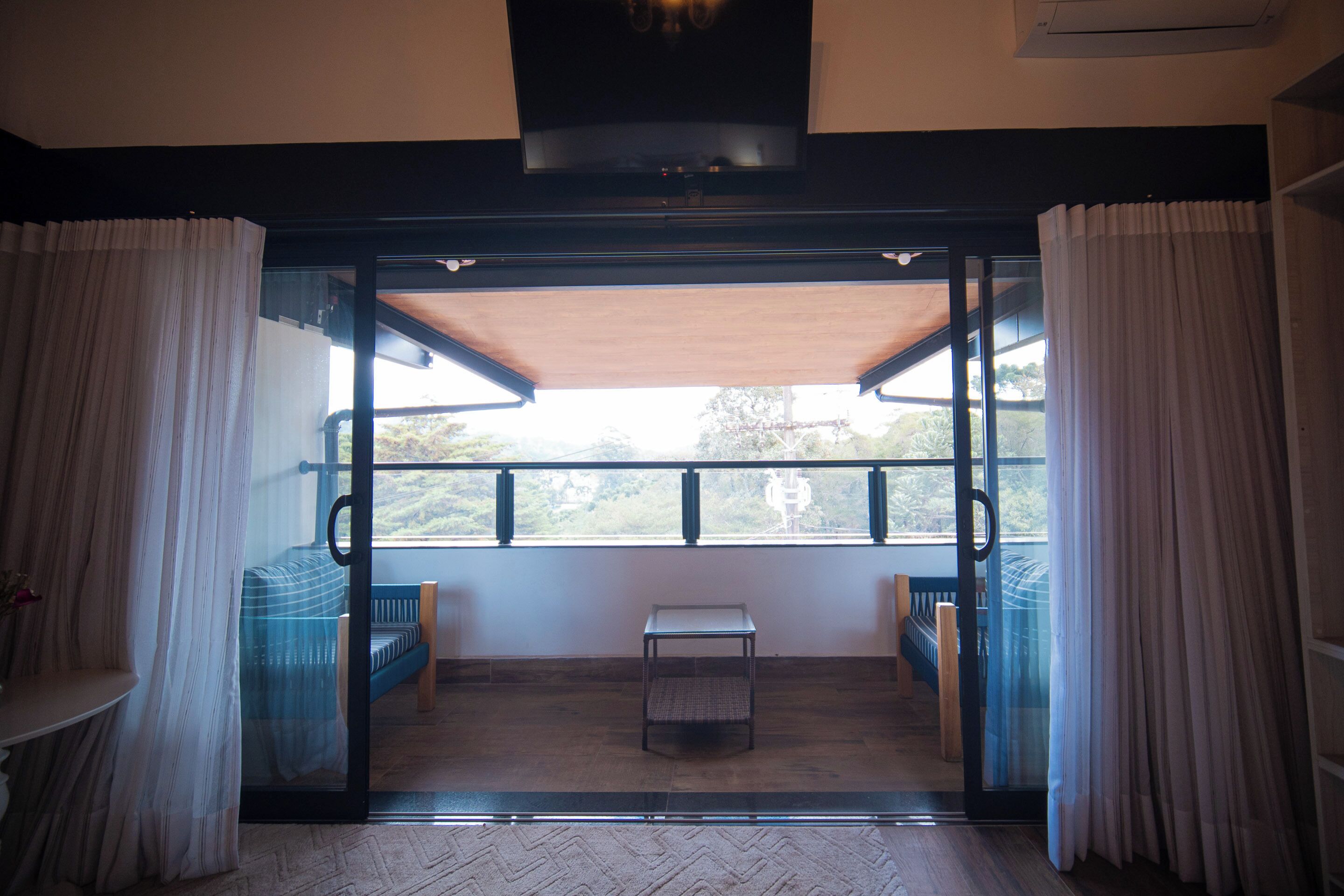 A room with a sliding glass door leading to a balcony with a view of greenery.