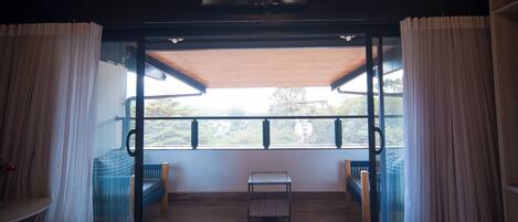 A room with a sliding glass door leading to a balcony with a view of greenery.