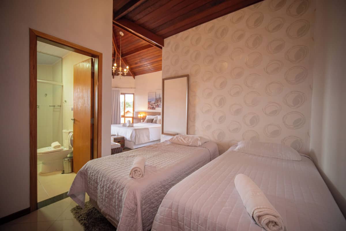 A hotel room with two beds, a bathroom, and a dining area.