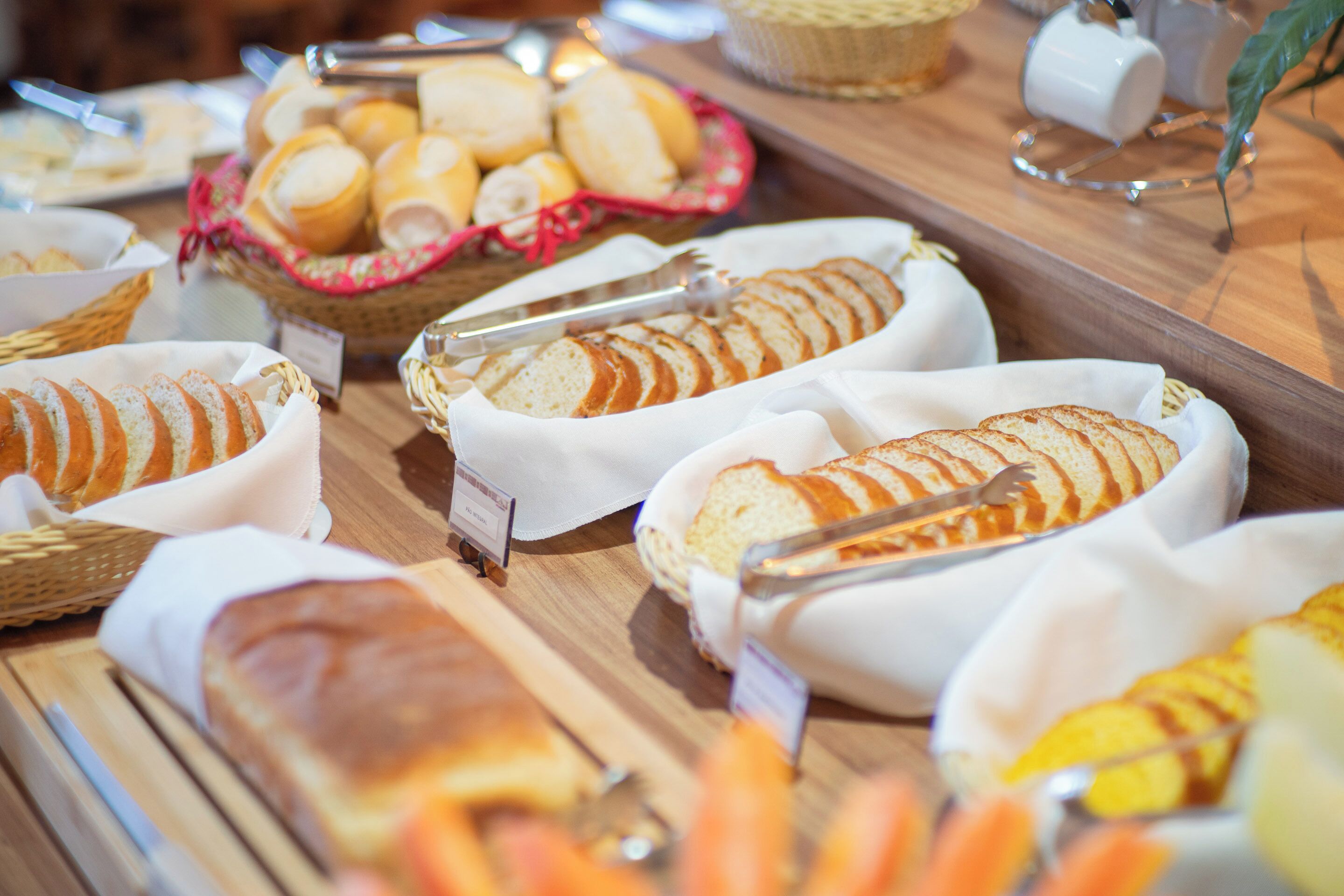 A buffet with various breads and pastries displayed in baskets and on a wooden board.