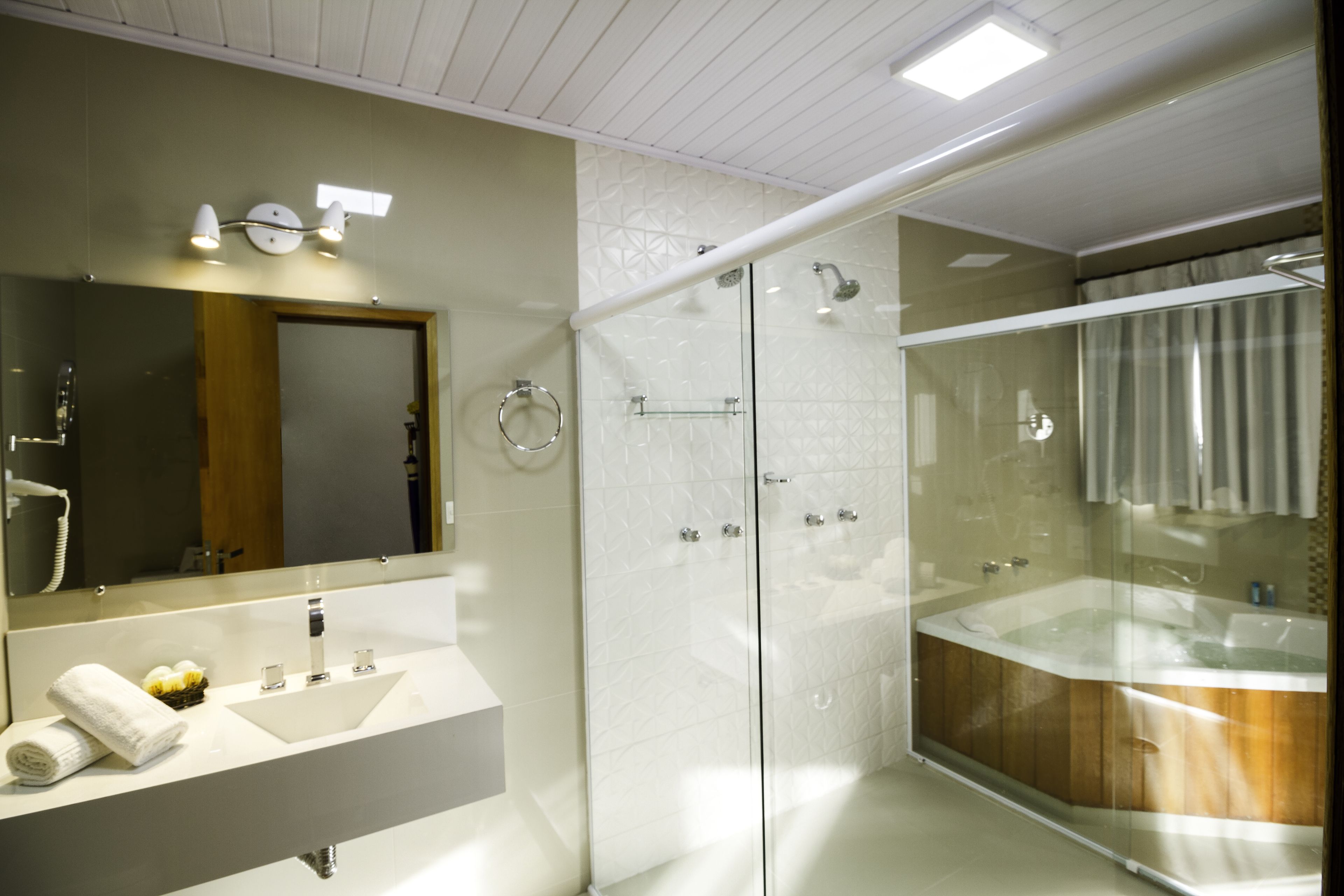 A modern bathroom with a glass-enclosed shower, a large bathtub, and a vanity with a mirror.