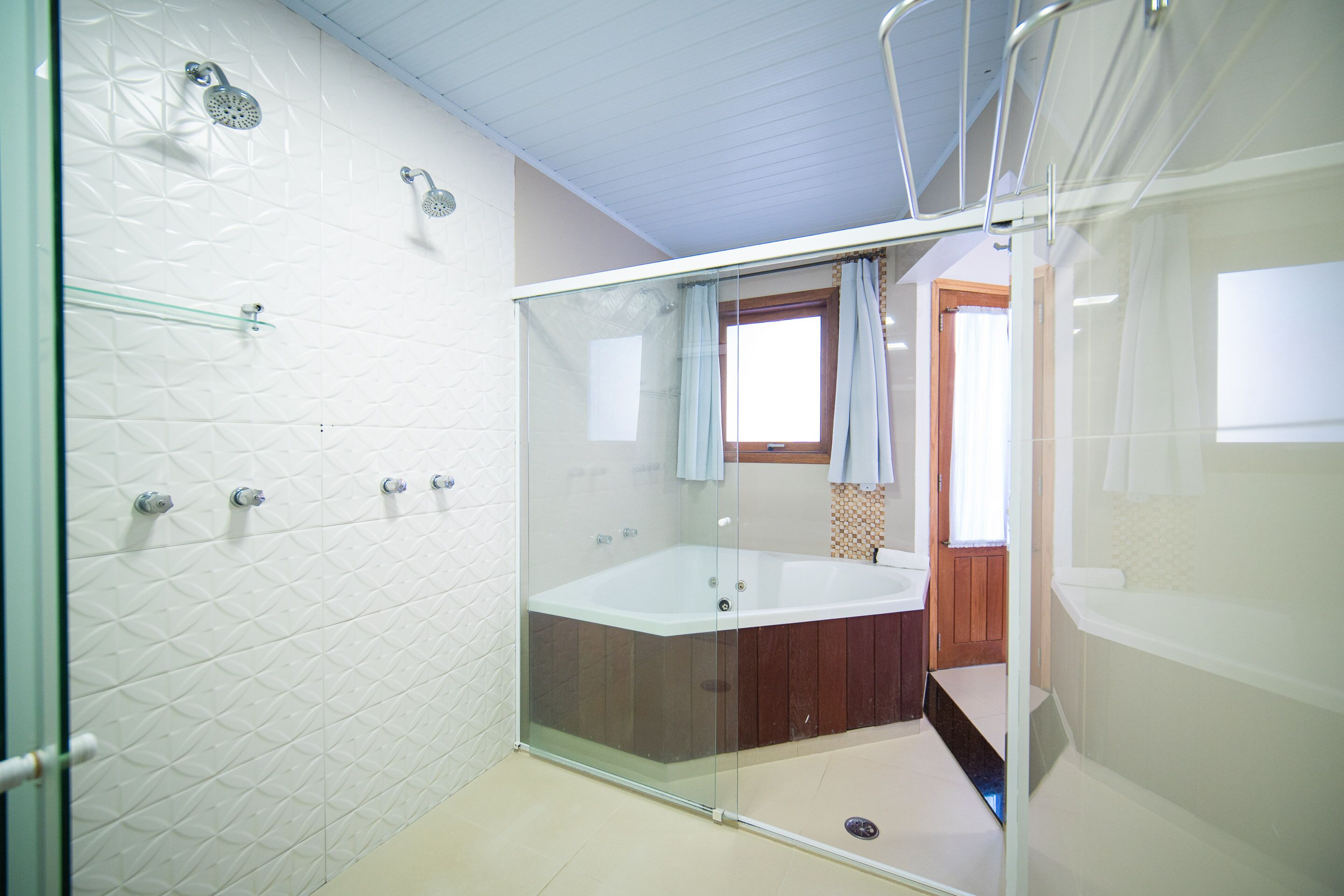 A modern bathroom with a glass-enclosed shower, a freestanding bathtub, and a wooden door leading to another room.