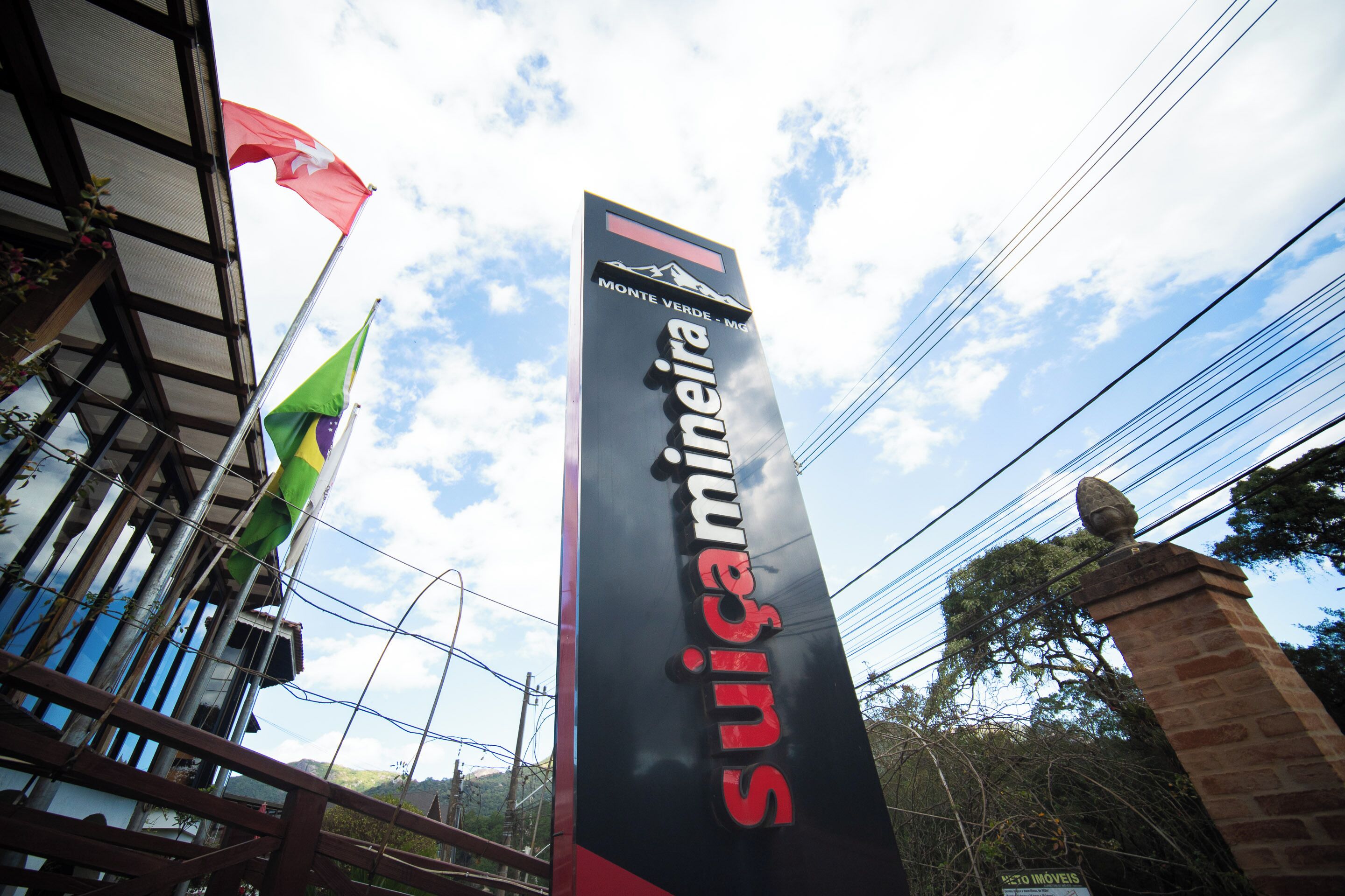A sign for 'Suicamina' with a mountain logo, a green flag, and a stone structure.