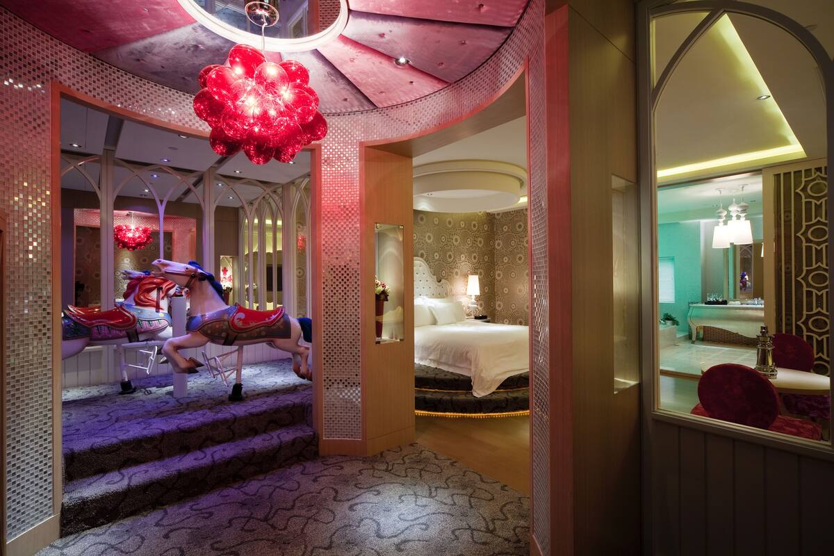 Een hotelkamer met een bed, een nachtkastje, een spiegel en een rode stoel.