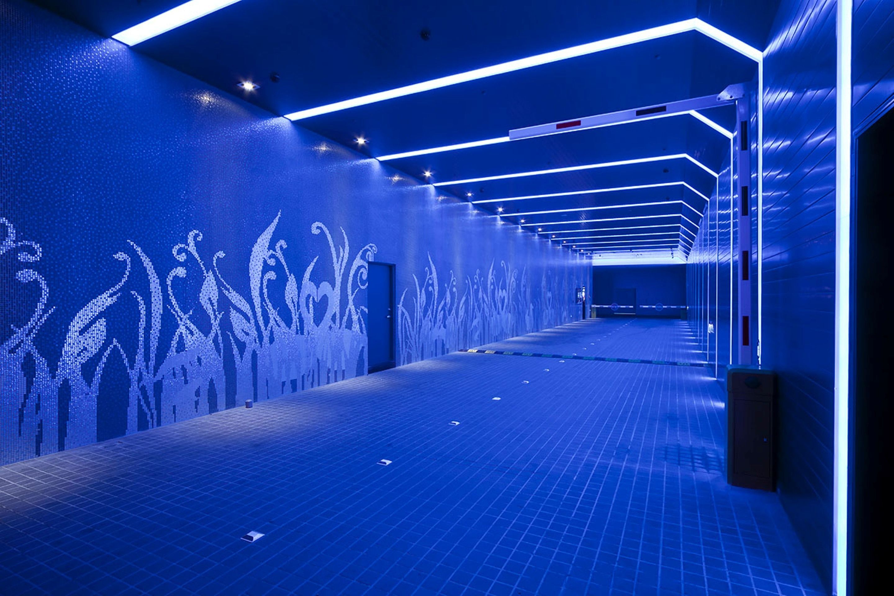 A modern hallway with geometric patterns on the walls and a tiled floor.