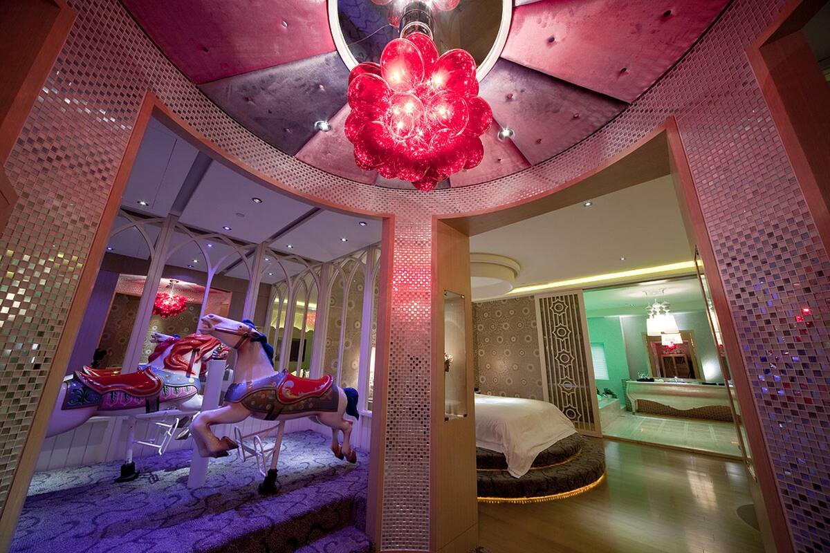 Een kamer met een draaimolen, een bed en een spiegel die de kamer weerkaatst.