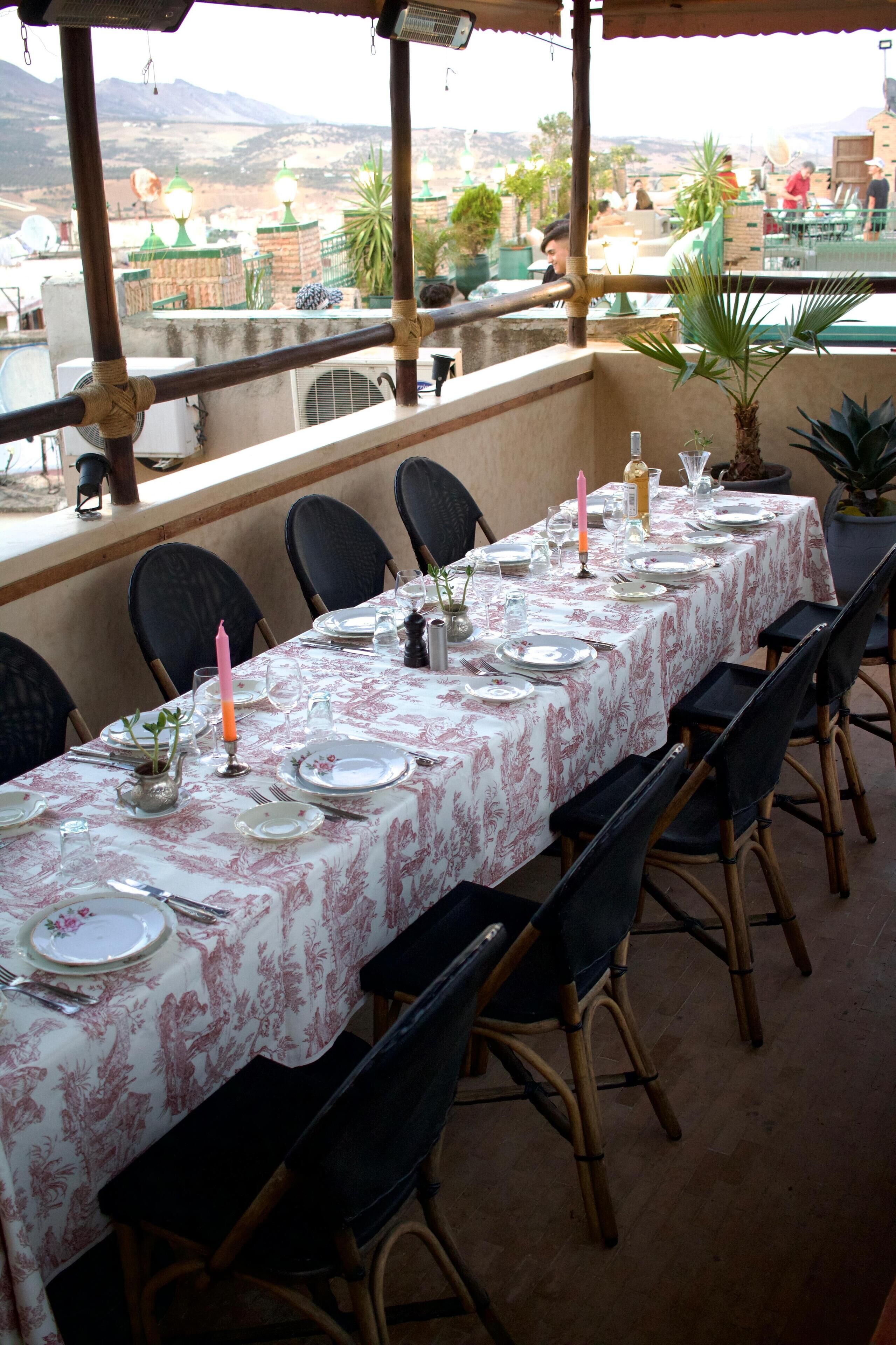 Een eettafel gedekt voor zes personen met stoelen, een uitzicht op de stad en een balkonhek.