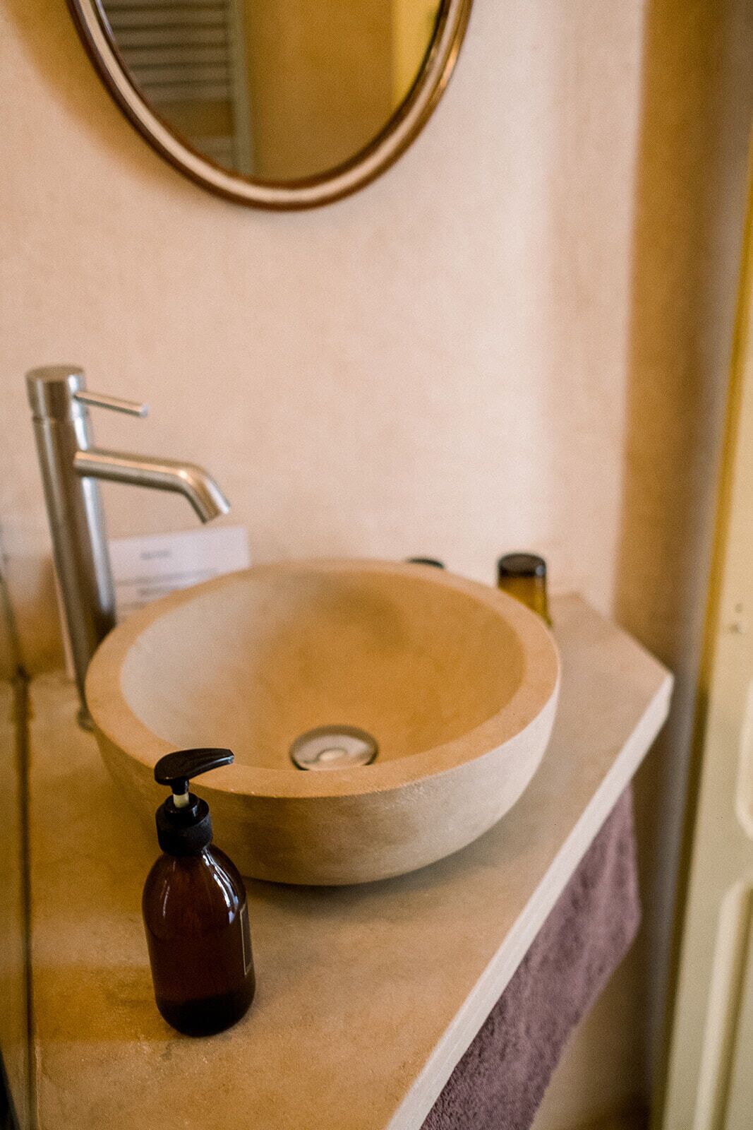 Un baño con un lavabo redondo, un grifo y un dispensador de jabón.