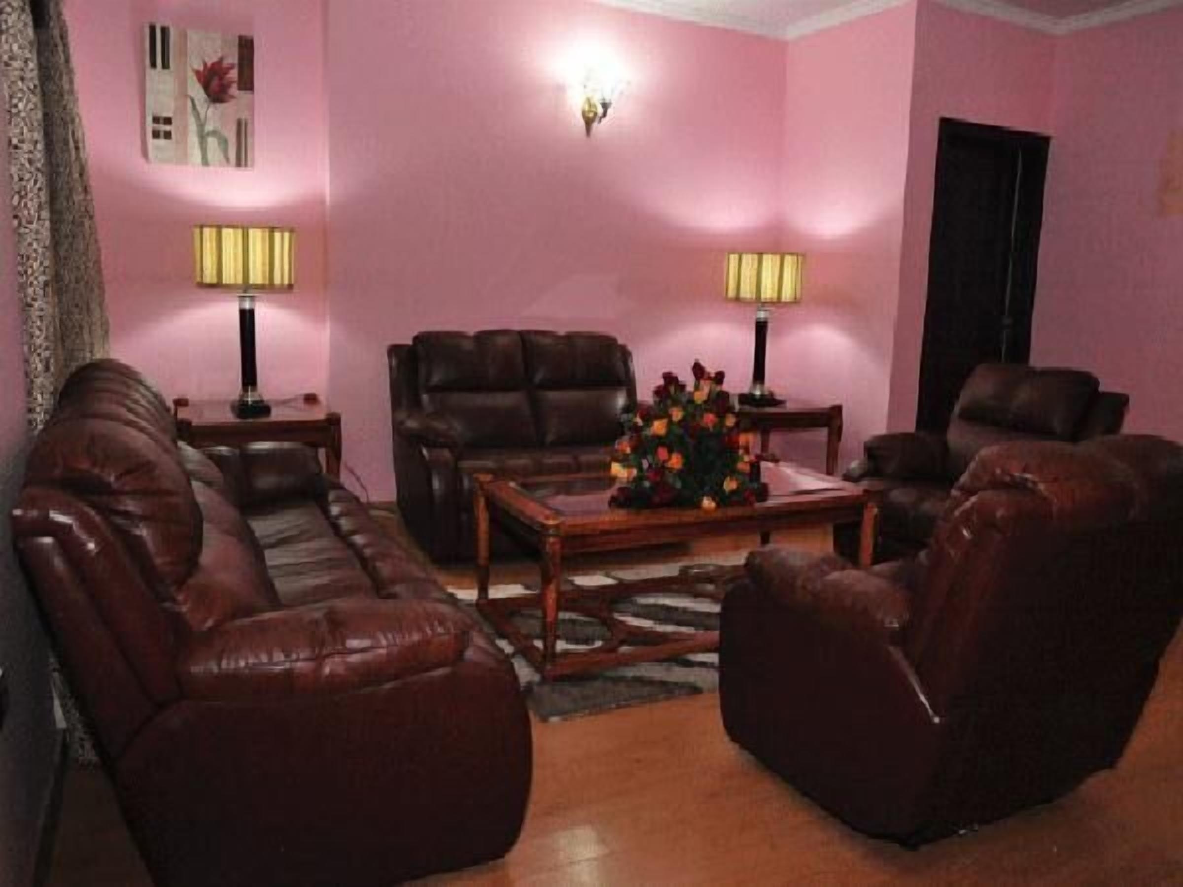 Una sala de estar con un sofá de cuero marrón, una mesa de centro de madera con un centro de mesa floral y dos lámparas de pie.