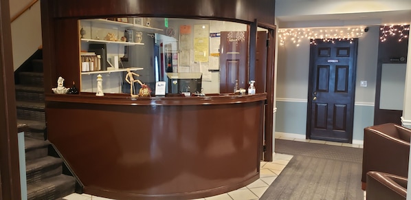 A reception desk with a mirror, a wooden counter, and a staircase to the left.