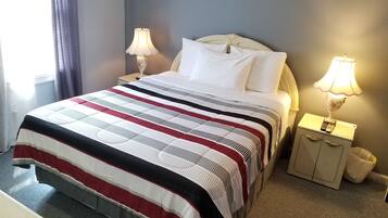 A neatly made bed with a striped bedspread, two bedside lamps, and a nightstand with a remote control.