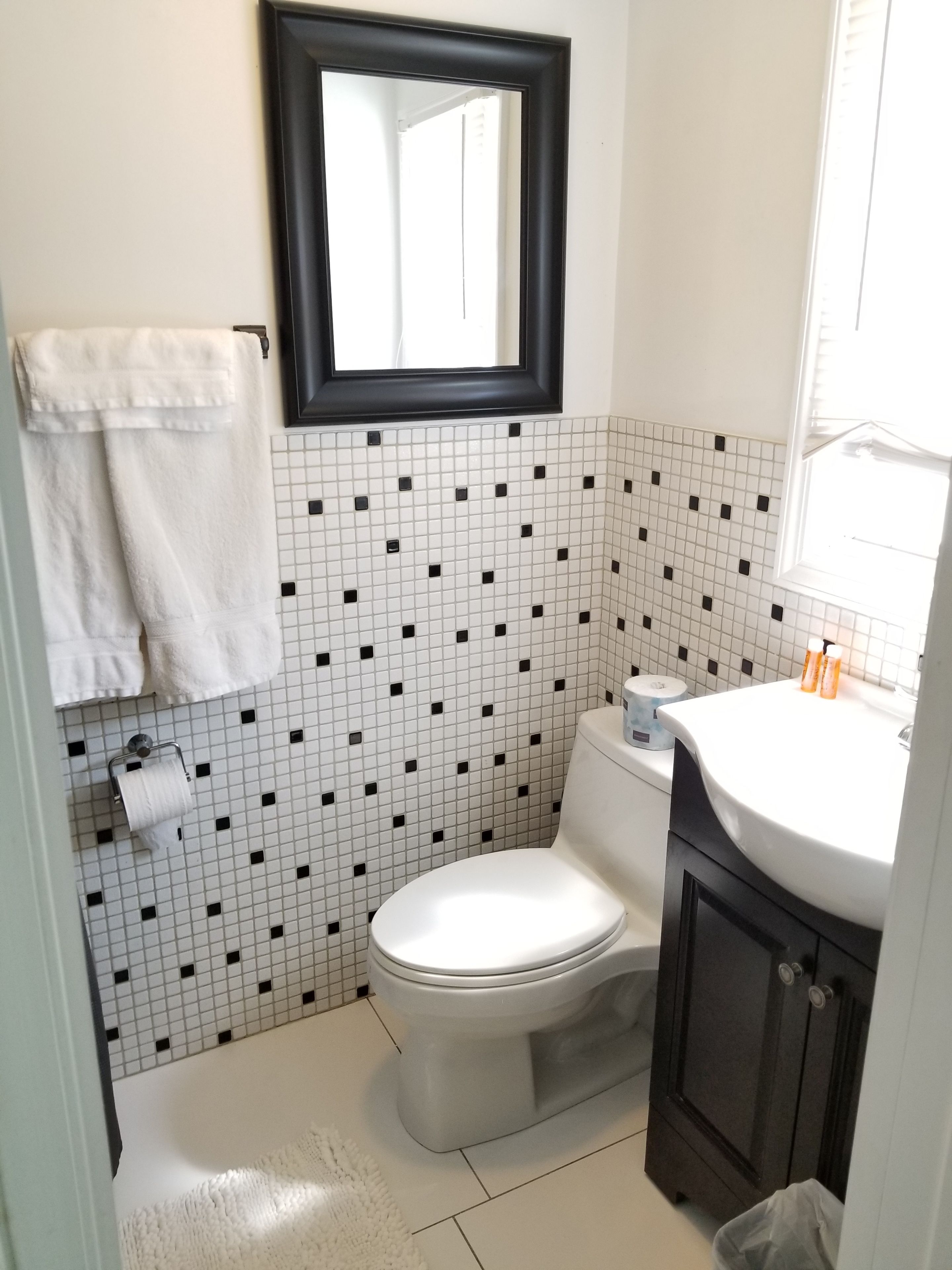 Een badkamer met toilet, wastafel, spiegel en handdoekhouder.