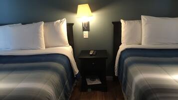 A hotel room with two beds, a nightstand with a lamp, and a small table with a menu.